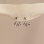 Starburst Cluster Ear Jackets in Sterling Silver, inspired by constellation earrings, displayed on a soft beige fabric background.