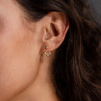 Close-up of a woman's ear wearing Starburst Cluster Ear Jackets in 18K Gold—delicate star and flower shapes, perfect for celestial jewelry lovers.