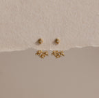 The Starburst Cluster Ear Jackets are displayed on a textured beige background, making them a perfect choice for fans of celestial jewelry.