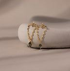 Agate Star Chain Earrings in 18K Gold feature gold chain drops with star-shaped studs and green agate gemstones, elegantly displayed on a smooth white stone.