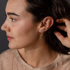 A woman in profile touches her hair against a dark background, wearing Agate Star Chain Earrings in Sterling Silver featuring green agate gems.