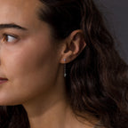 A woman with long wavy hair wears Agate Diamond Dangle Earrings, modern essential jewelry, shown from the side against a dark background.