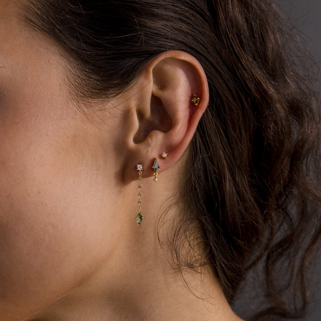 Close-up of a woman's ear adorned with Agate Diamond Dangle Earrings, modern essential jewelry that gleams against a dark background.
