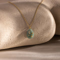 Celestial Aventurine Pendant Necklace with a green aventurine oval pendant, crescent moon and star charms, shown on a stone background.