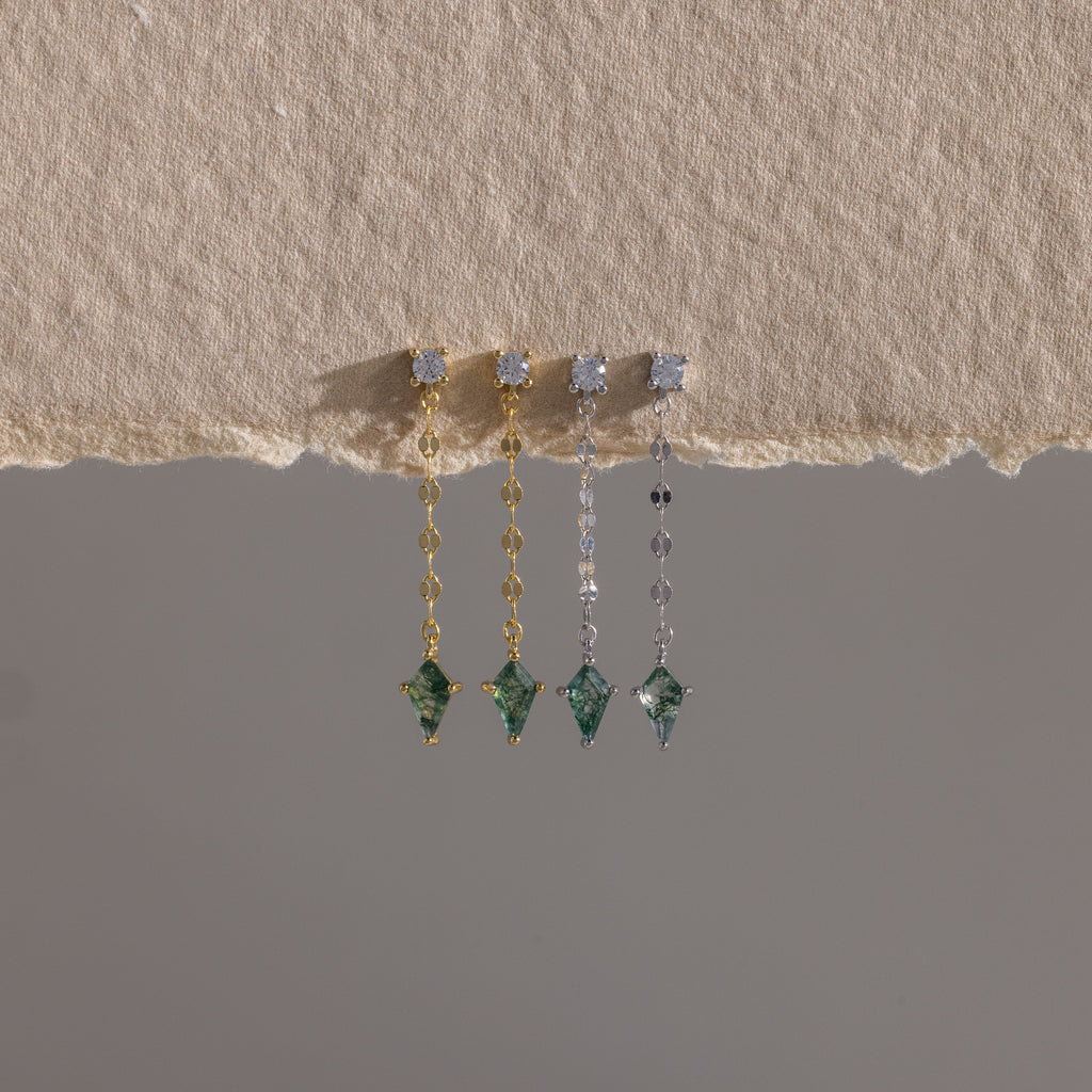 Four Agate Diamond Dangle Earrings with green gemstones in gold and silver, displayed on textured beige fabric—showcasing modern essential jewelry.