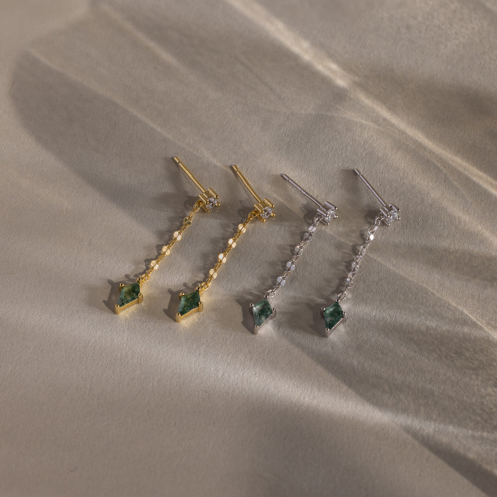 The Agate Diamond Dangle Earrings come in gold and silver, each featuring a green gemstone and clear stones—modern essentials for any look.