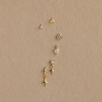Six 18K gold Opal Cluster Flatback Studs with opal and star designs, arranged vertically on a textured beige background—perfect for an iridescent opals-inspired ear stack.