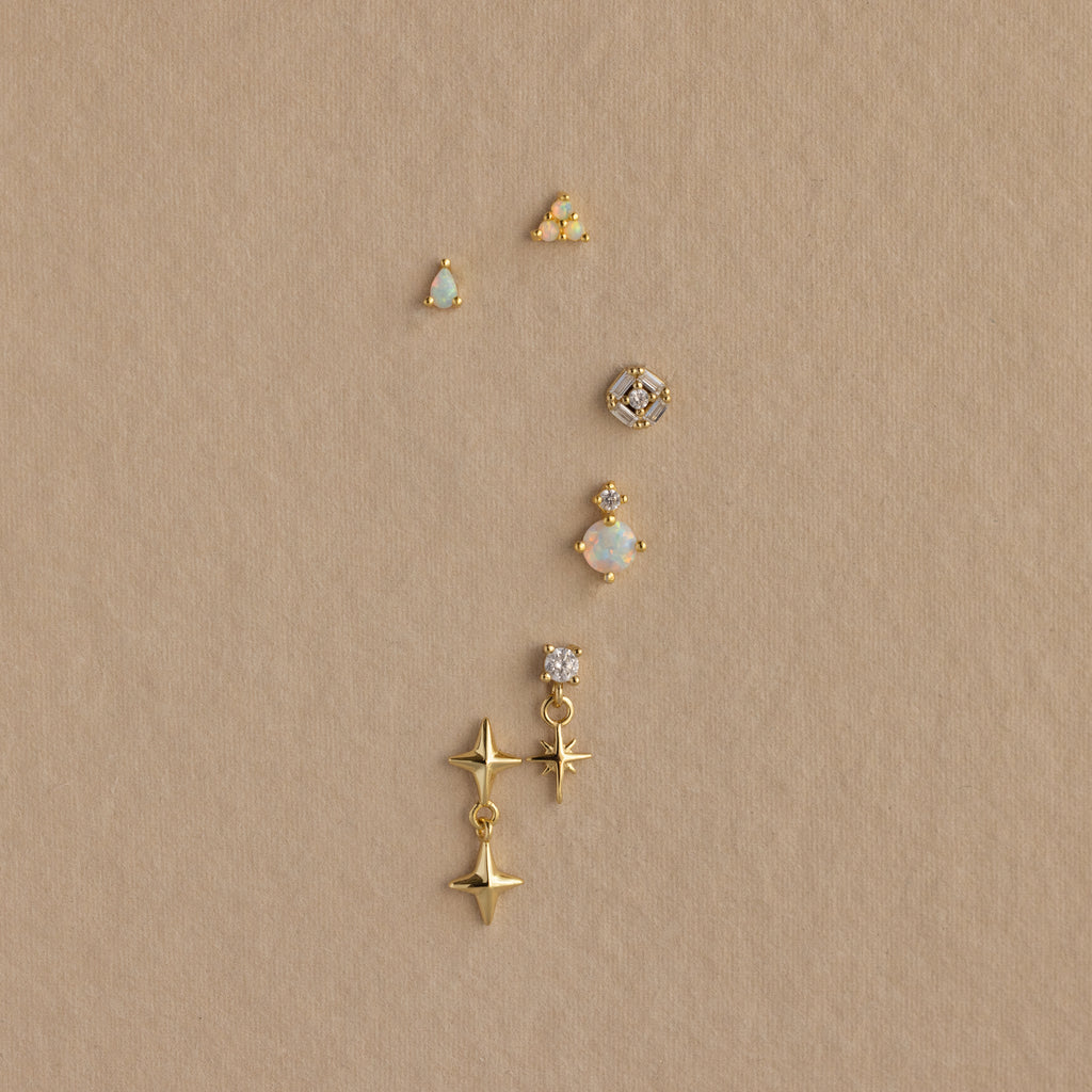 Six Opal Teardrop Flatback Studs in 18K Gold, perfect for minimalist earring stacks or cartilage piercings, displayed on a tan textured background.