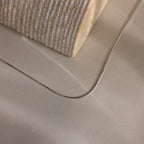 The Dainty Herringbone Necklace is displayed resting on a beige surface beside a textured block.