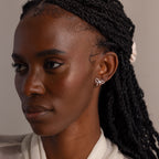 Model wearing silver bow-shaped stud earrings with sparkling stones, styled with a cream blouse for an elegant, refined look.