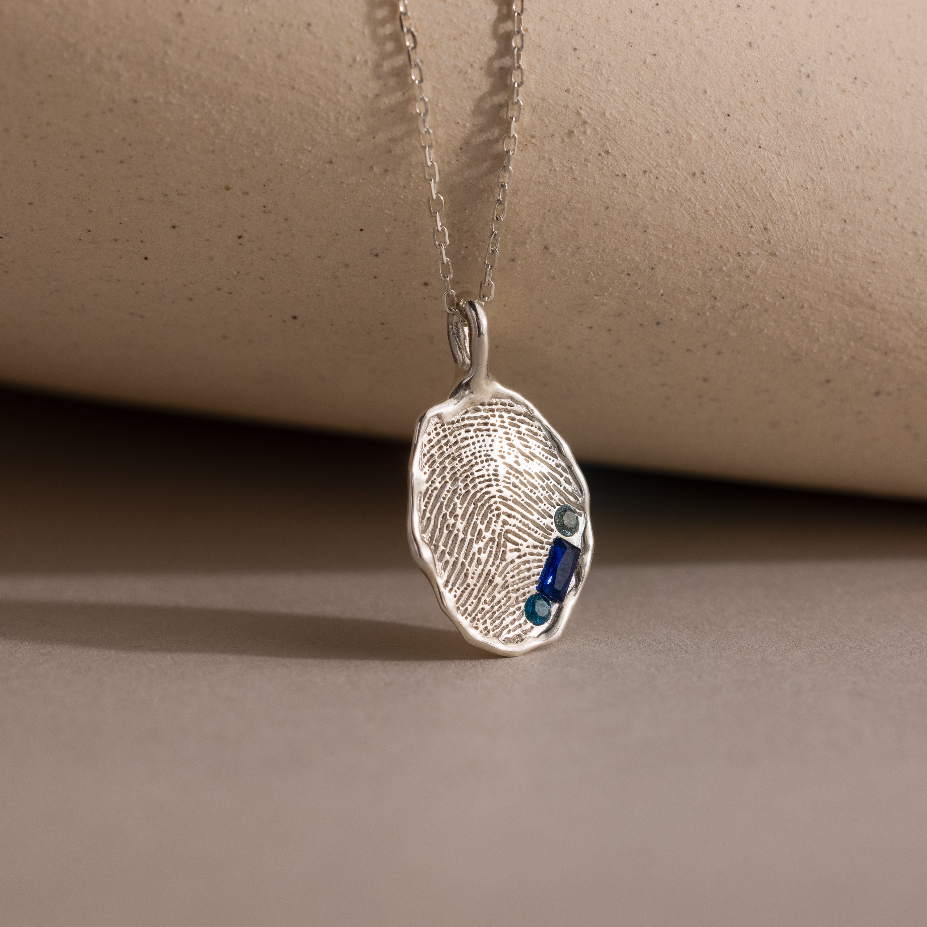Organic Fingerprint Multi Birthstone Necklace with a fingerprint design and multiple birthstones, displayed on a neutral surface—an ideal personalized family keepsake for capturing cherished memories.