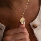 A person holds the Organic Fingerprint Multi Birthstone Necklace in Rose Gold close to their chest—a striking, personalized piece featuring unique fingerprints and sparkling birthstones.