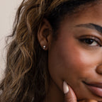 A close-up of a woman's face highlights her Moonstone Orbit Studs in sterling silver as she rests her hand on her chin.