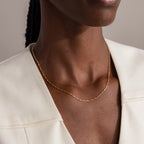 A woman in a cream-colored blazer completes her look with the Dot Station Necklace—a minimalist gold piece featuring simple dots on a delicate chain.