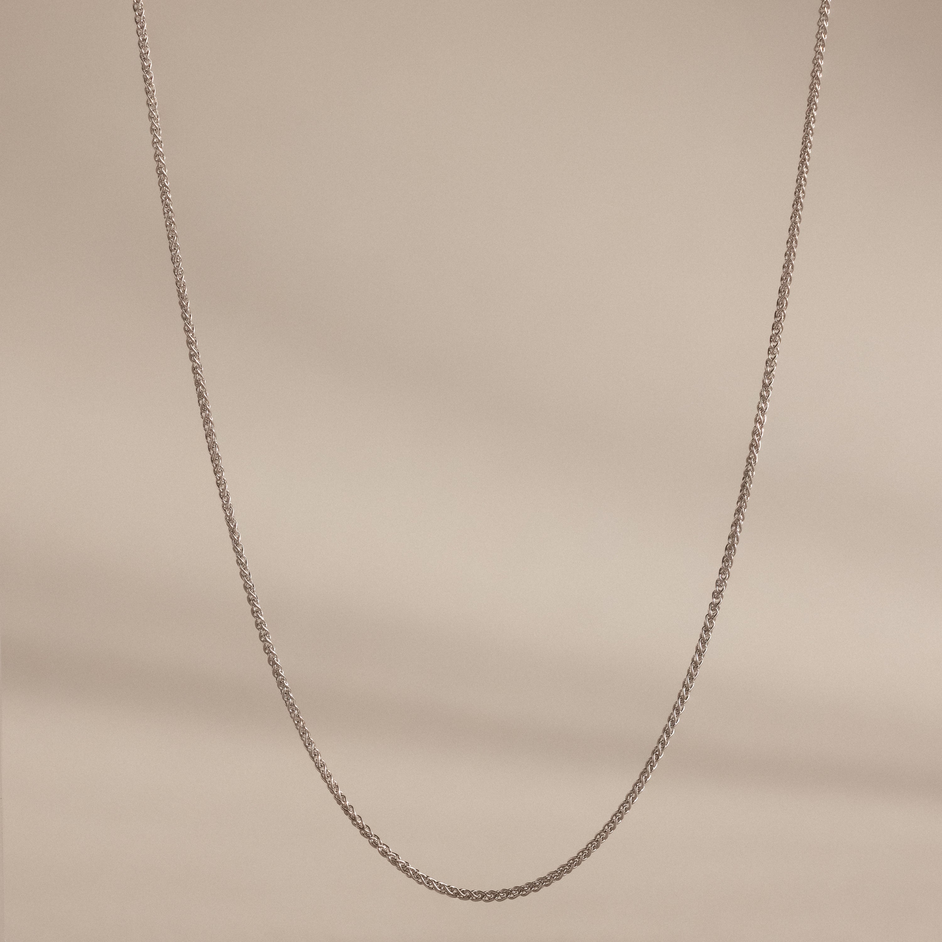 The Woven Chain Necklace is showcased against a neutral beige background.