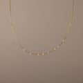 The Sprinkle Diamond Necklace in 18K Gold features a delicate chain adorned with small, evenly spaced diamonds, shown against a plain beige background.