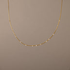 The Sprinkle Diamond Necklace in 18K Gold features a delicate chain adorned with small, evenly spaced diamonds, shown against a plain beige background.