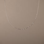 The Sprinkle Diamond Necklace in Silver, featuring delicate, evenly spaced beads, is displayed against a plain beige background.