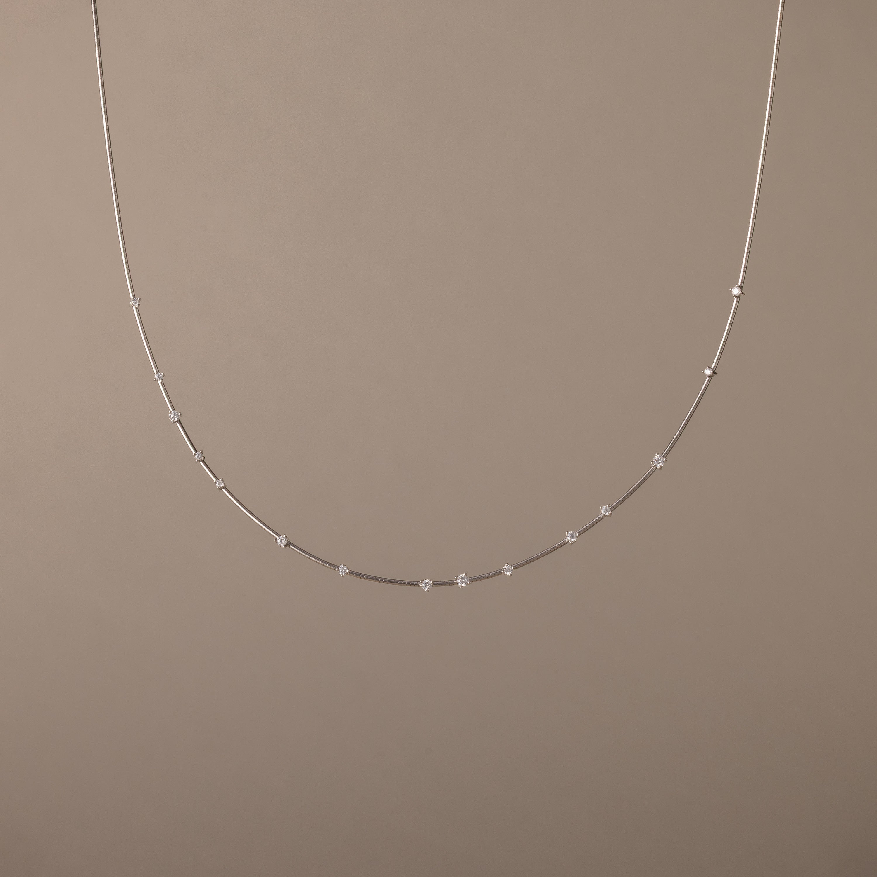 The Sprinkle Diamond Necklace in Silver, featuring delicate, evenly spaced beads, is displayed against a plain beige background.