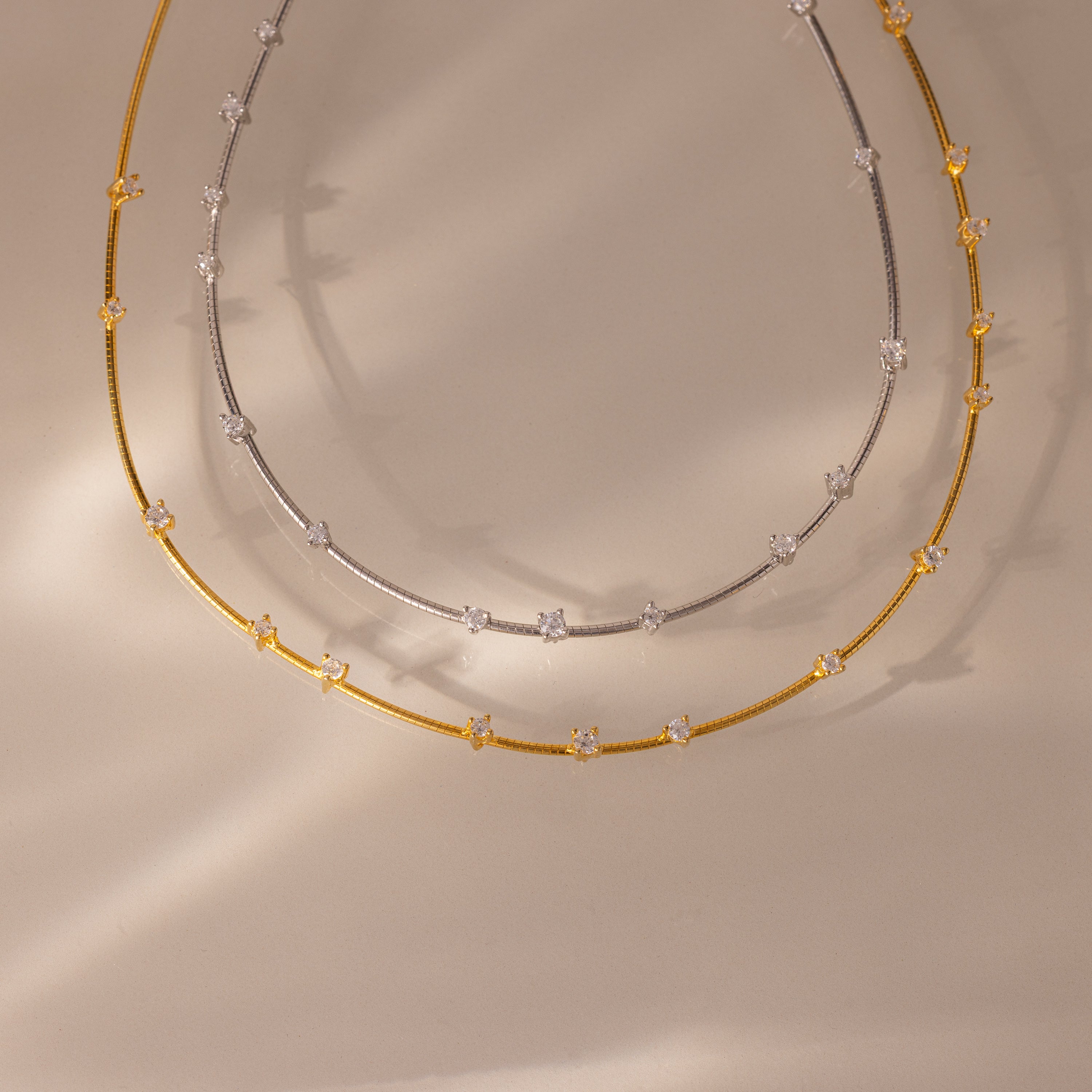 The Sprinkle Diamond Necklace collection features two delicate chain necklaces, one gold and one silver, each adorned with sparkling stones—perfect for capturing everyday brilliance.