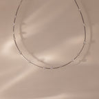 The Sprinkle Diamond Necklace in Silver features a fine, delicate chain with small, evenly spaced diamonds on a soft beige background. Perfect for layering and adding an elegant touch to any look.