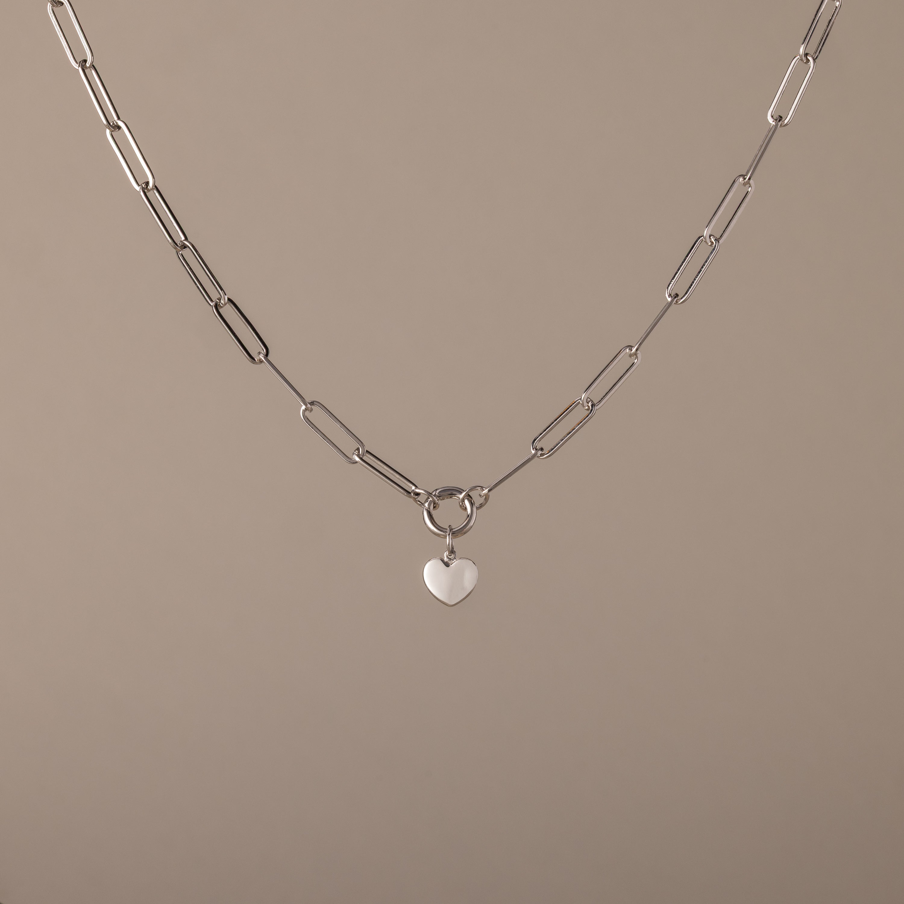 The Paperclip Heart Charm Necklace in Silver features elongated links and a small heart-shaped pendant—a delicate accessory perfect for everyday wear.
