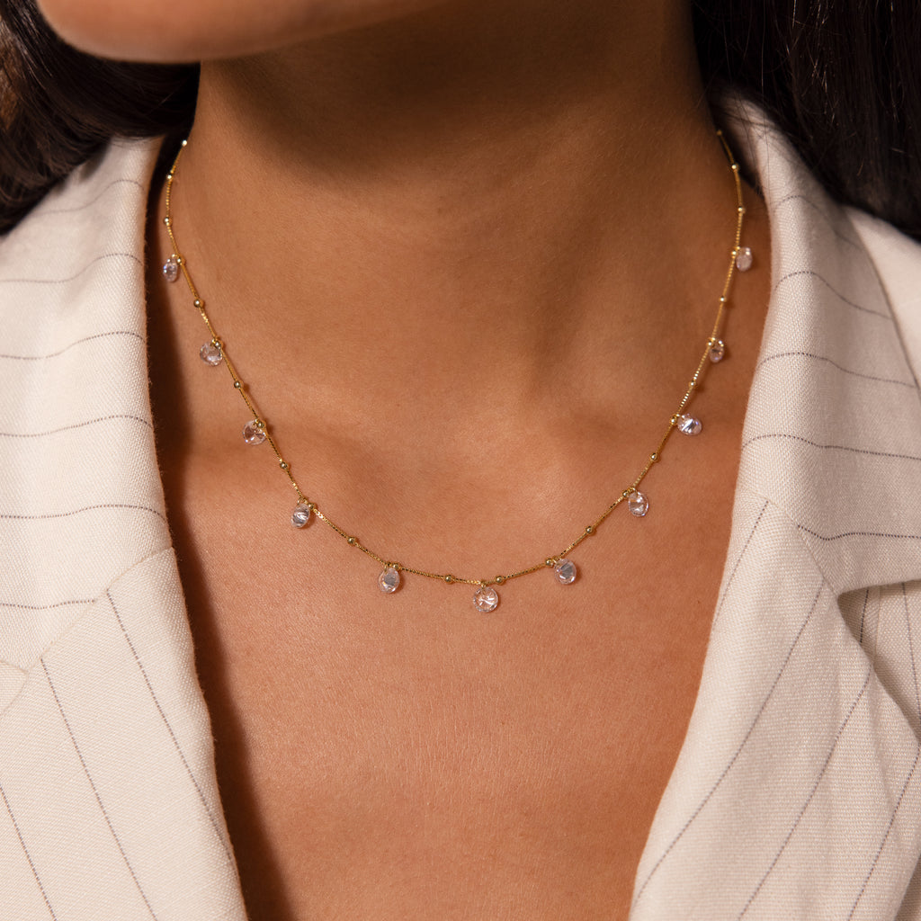 A woman wears the Satellite Diamond Necklace in 18K Gold, paired with a cream pinstripe blazer.