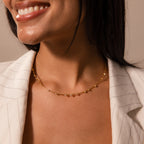 A woman wearing the Sprinkle Diamond Necklace with a delicate chain and a light pinstriped blazer smiles softly—an effortless touch of brilliance for every day.