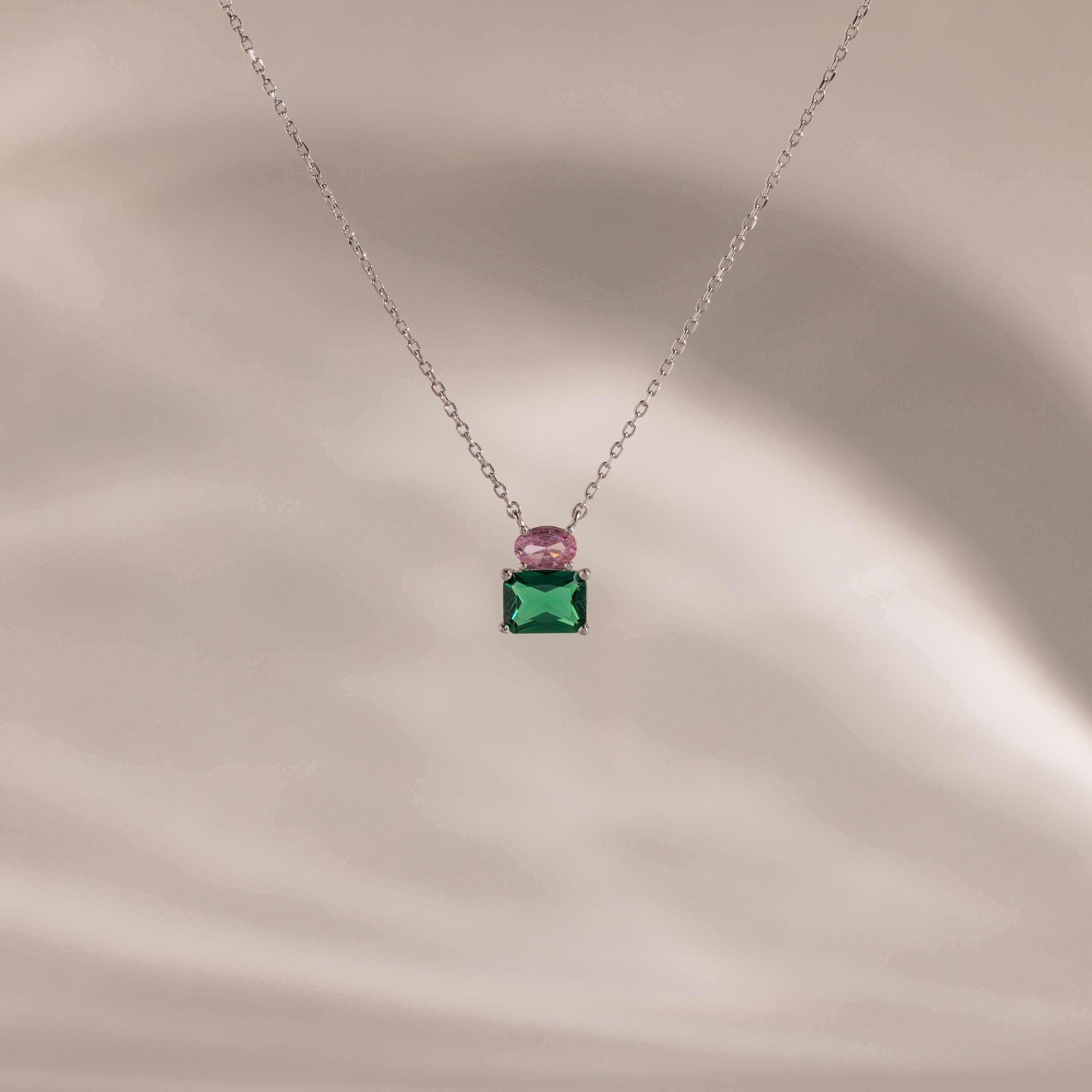 Flatlay of our Emerald Bloom Necklace with Pink Tourmaline and Emerald gemstones.