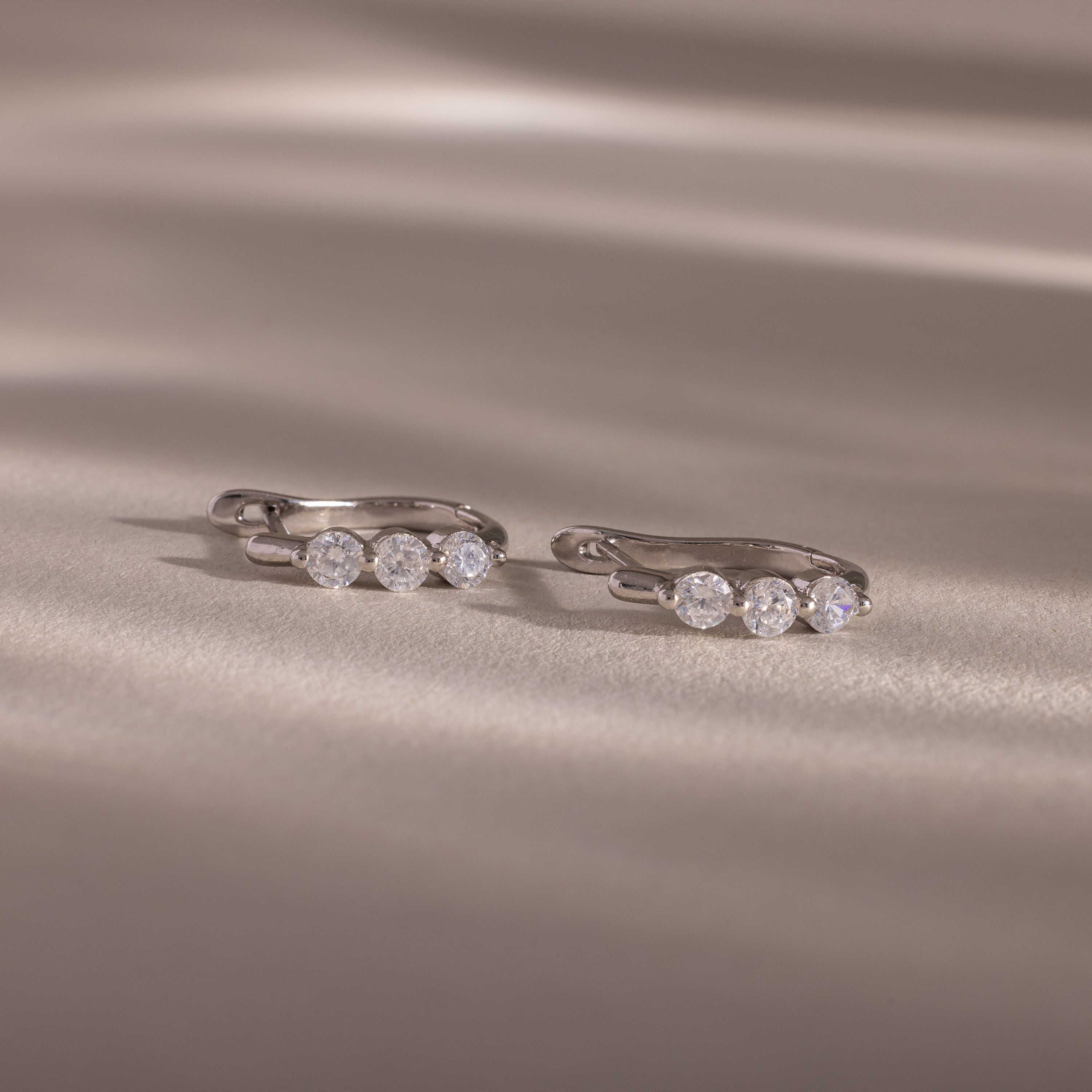 Flatlay of our Lace Diamond Hoops in Sterling Silver on a beige fabric background