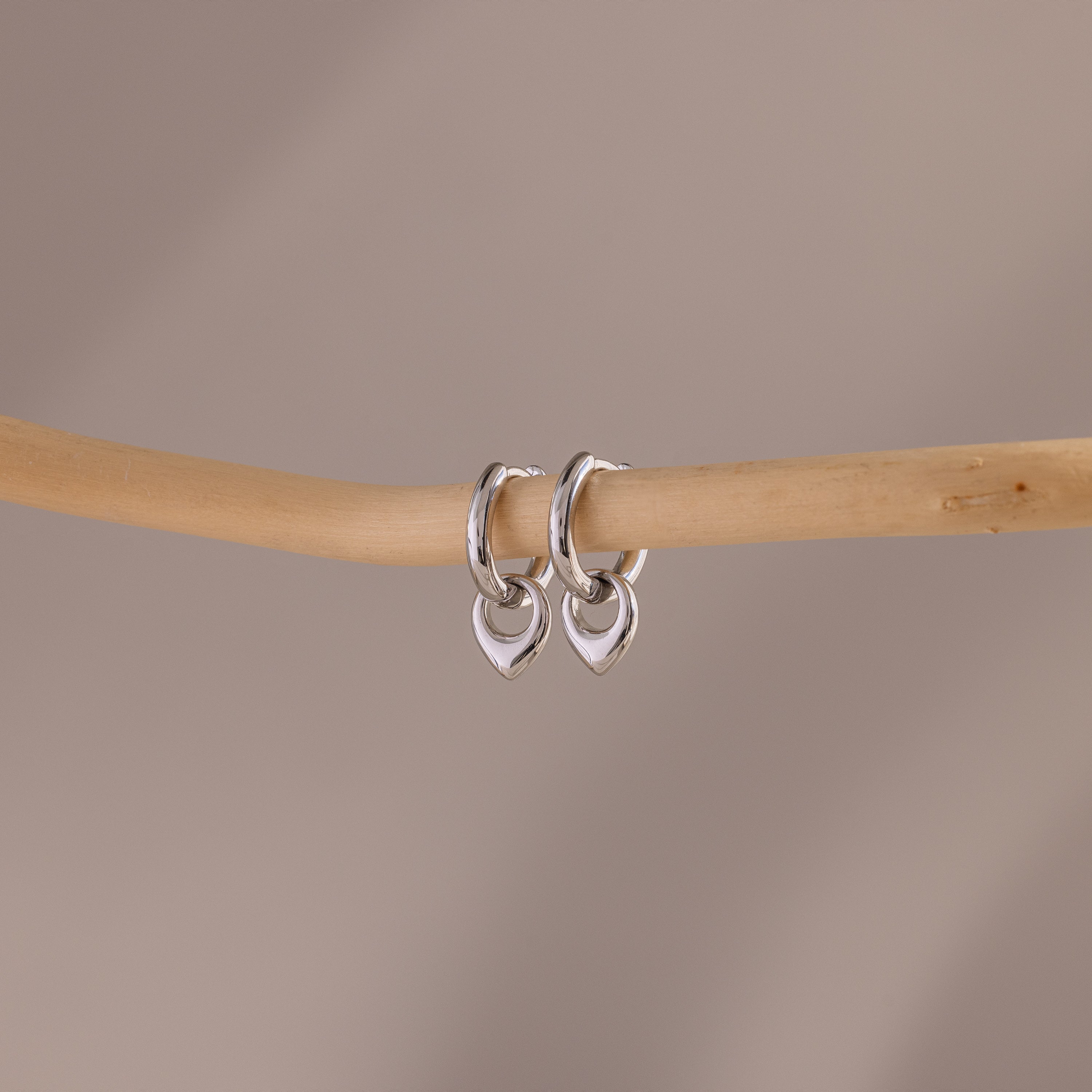 Flatlay of our Tiny Teardrop Huggies in White Gold