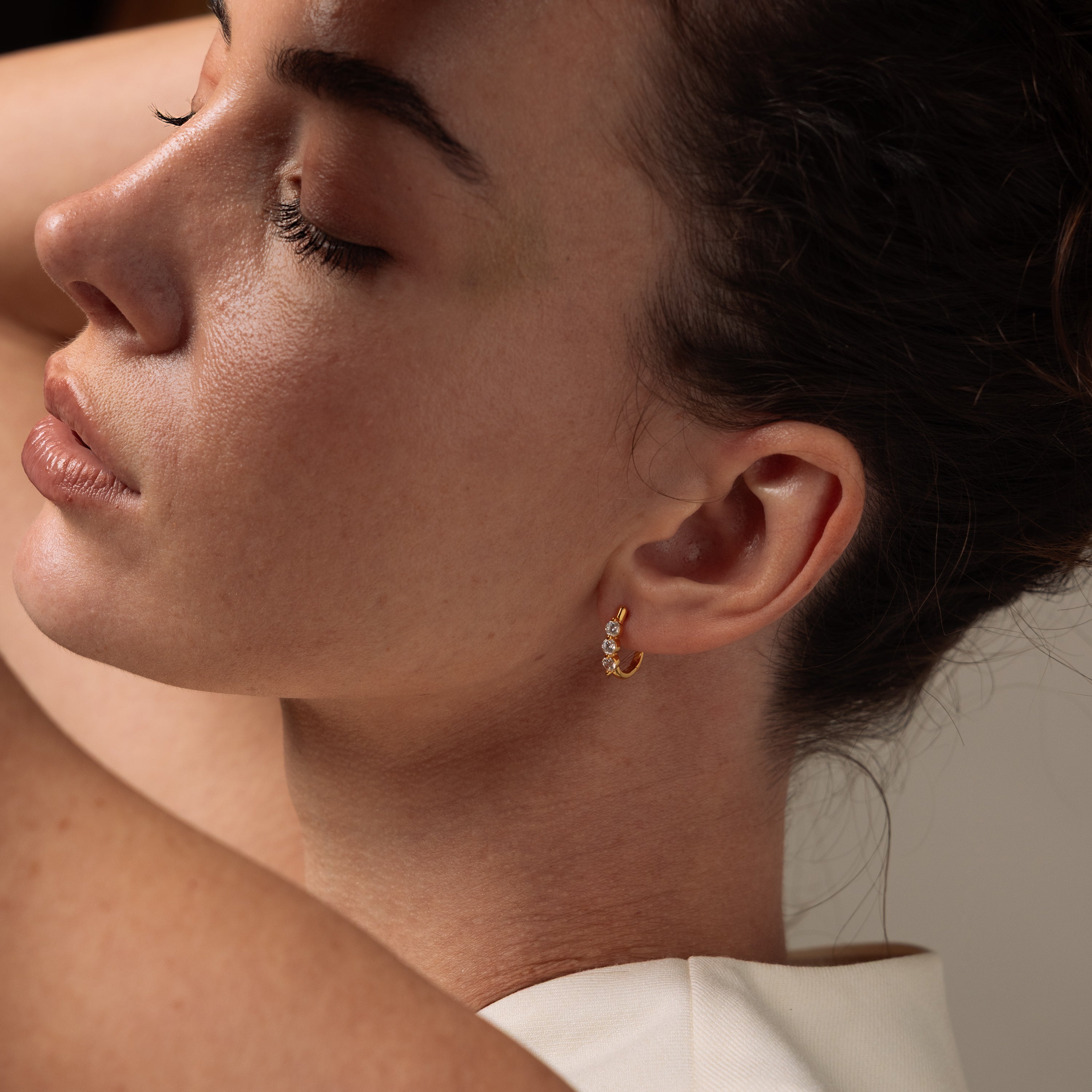 Close-up of a woman wearing our Lace Diamond Hoops in Gold with a neutral background