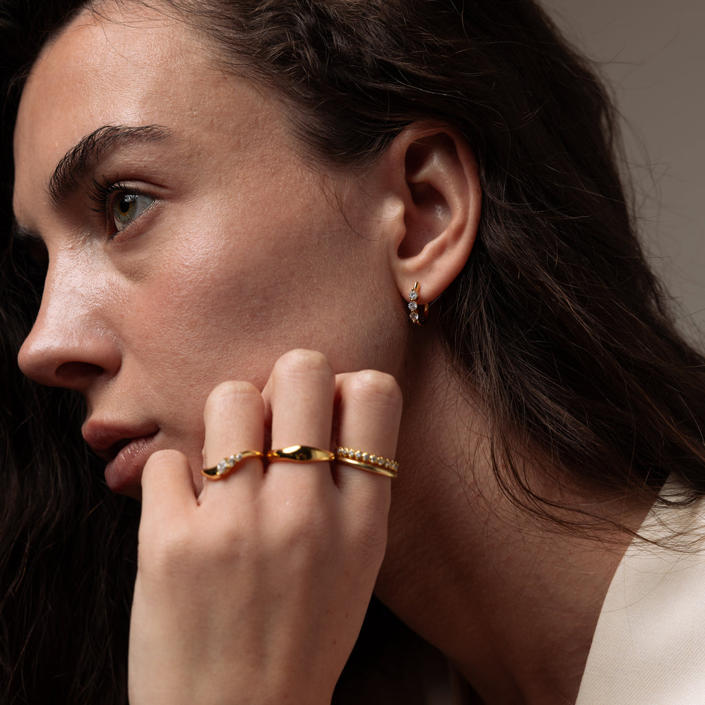 Close-up of a model wearing our Lace Diamond Hoops in Gold, styled with an ring stack