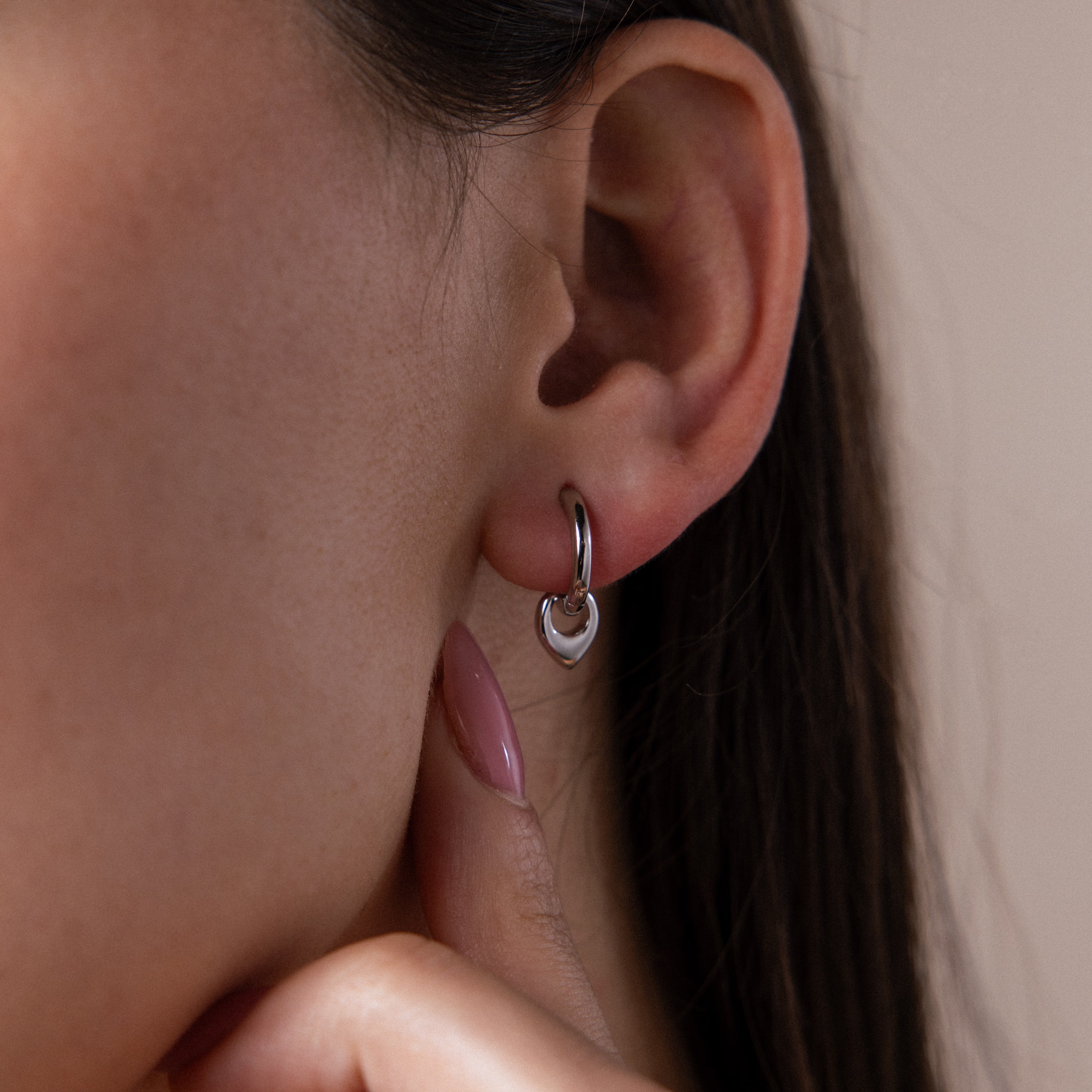 Close up of a model wearing our Tiny Teardrop Huggies in White Gold