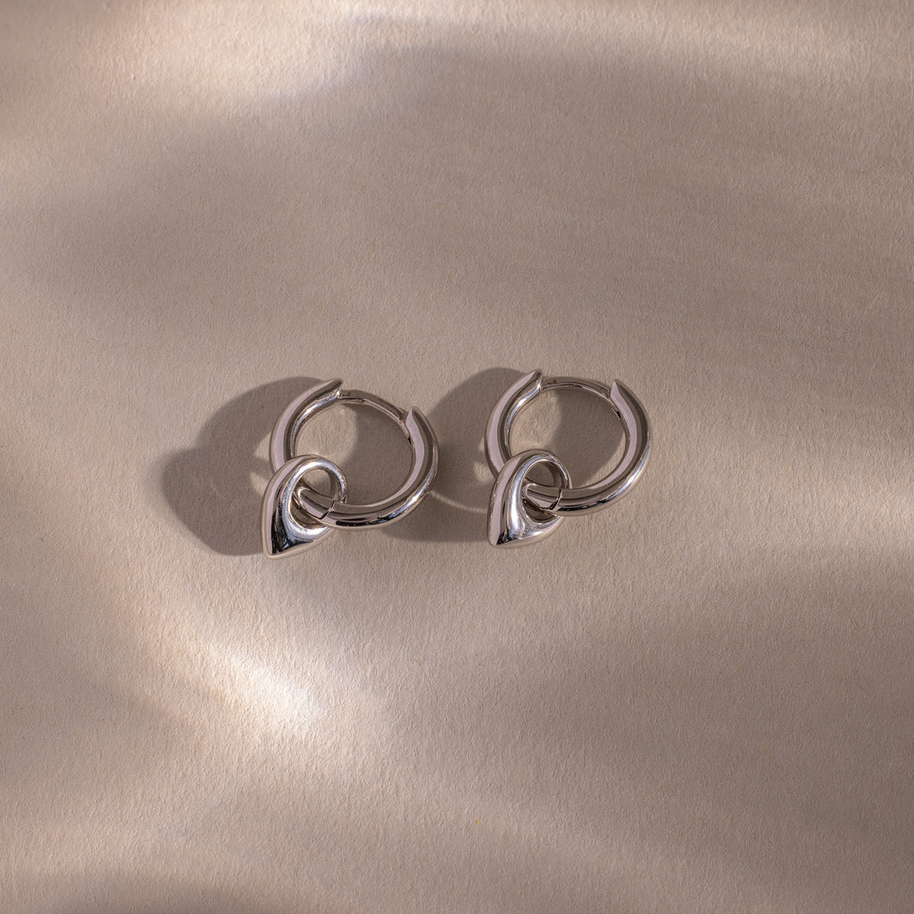 Close up flatlay of our Tiny Teardrop Huggies in White Gold