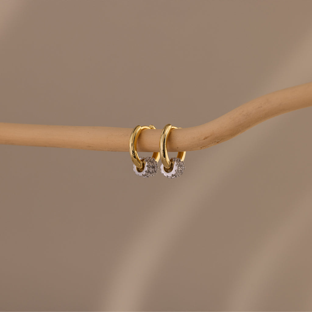 Image of our Mixed Metal Pave Hoops in 18K Gold, hung on a wooden stick