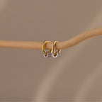 Image of our Mixed Metal Pave Hoops in 18K Gold, hung on a wooden stick