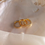 The Pave Birthstone Charm Clip shines with colorful gemstones, displayed on a smooth, iridescent shell surface.
