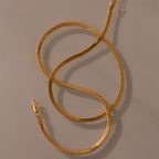 The Bold Snake Chain Necklace in 18K Gold features a lobster clasp and modern design, shown in an S shape on a neutral background—perfect for layering.