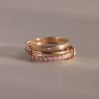 The Triple Linked Pink Tourmaline Ring Set, featuring rose gold bands with pink stones, is displayed on a neutral background.