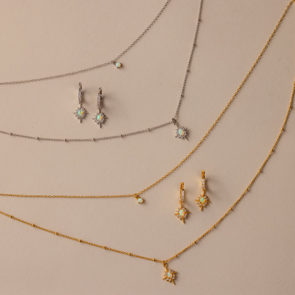 The Opal Star Necklace & Earrings Set in Silver is displayed on a beige background.