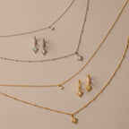 The Opal Star Necklace & Earrings Set in Silver is displayed on a beige background.