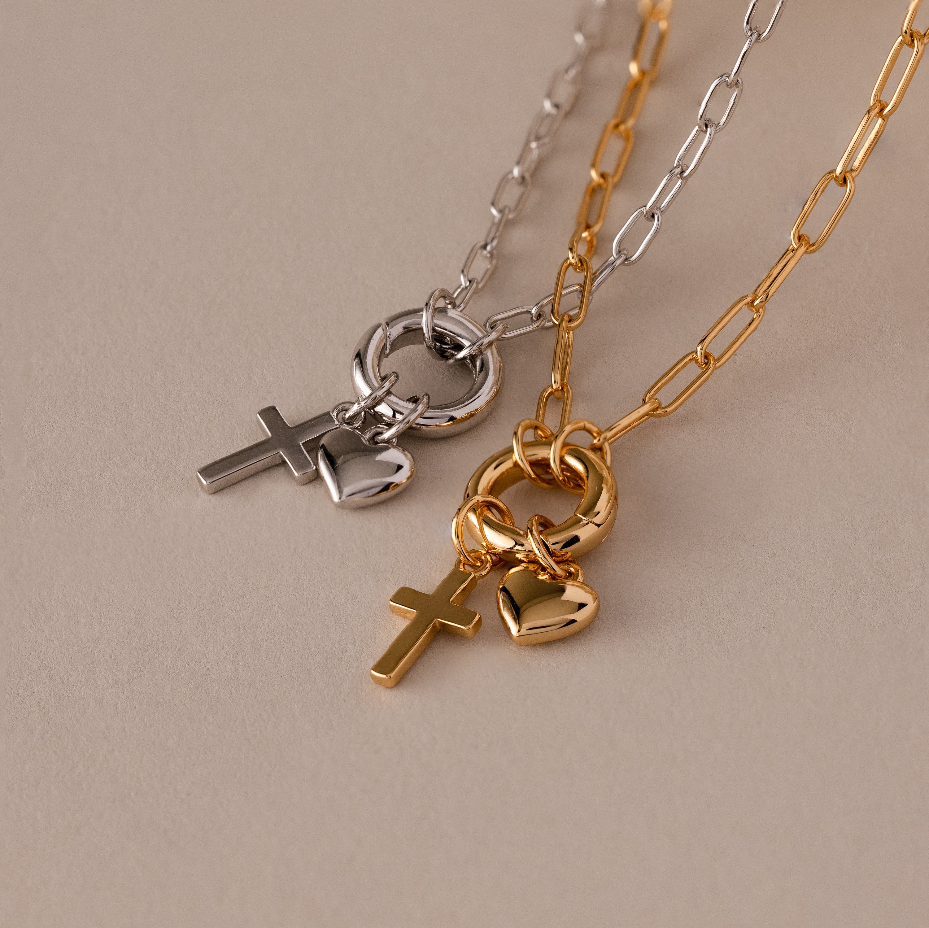 The Cross & Heart Charm Bracelet, featuring elegant gold and silver tones with cross and heart pendants, captures the timeless style of minimalist accessories on a chic beige background.