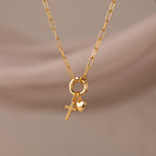 Cross & Heart Charm Bracelet in 18K Gold, featuring cross and heart charms on a stylish paperclip chain, displayed against a soft beige background.