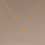 The Vintage Cross Necklace in 18K Gold features a pavé-finished, diamond-studded cross pendant displayed on a simple light brown background.