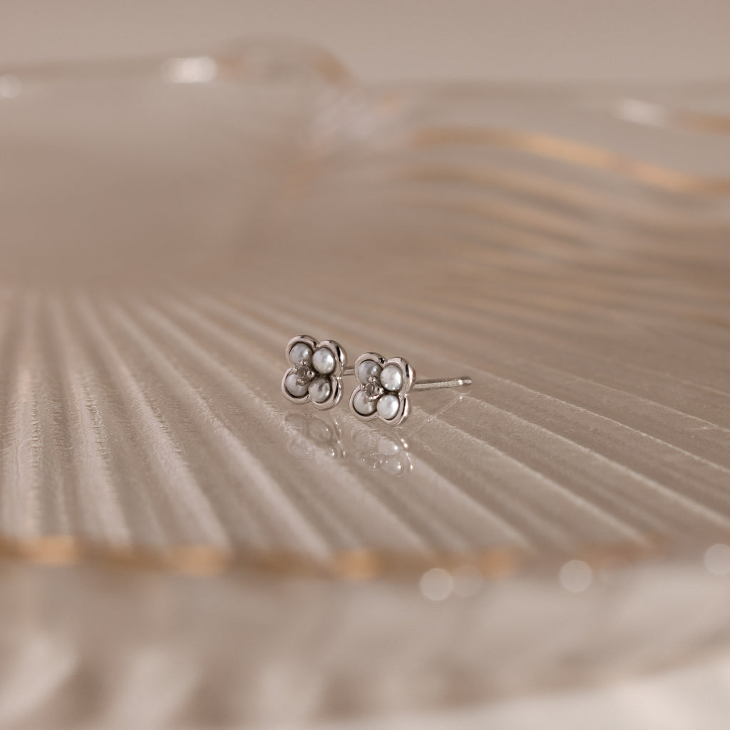 Rounded Pearl Flower Studs in Sterling Silver, featuring small pearls in a floral design, displayed on translucent ribbed glass—an elegant choice for bridesmaid jewelry at any special occasion.