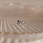 Rounded Pearl Flower Studs in Sterling Silver, featuring small pearls in a floral design, displayed on translucent ribbed glass—an elegant choice for bridesmaid jewelry at any special occasion.