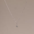 The Rounded Pearl Flower Necklace in Sterling Silver features a delicate chain and a small, three-pearl floral pendant, perfect for everyday layering and adding subtle elegance to any neutral background.