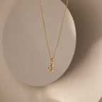 The Rounded Pearl Flower Necklace in 18K Gold features a pearl flower pendant, elegantly set against a neutral round backdrop.