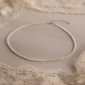 The Summer Pearl Beaded Necklace in Sterling Silver is displayed on a beige lace fabric background, making it the perfect choice for modern pearl jewelry this summer.